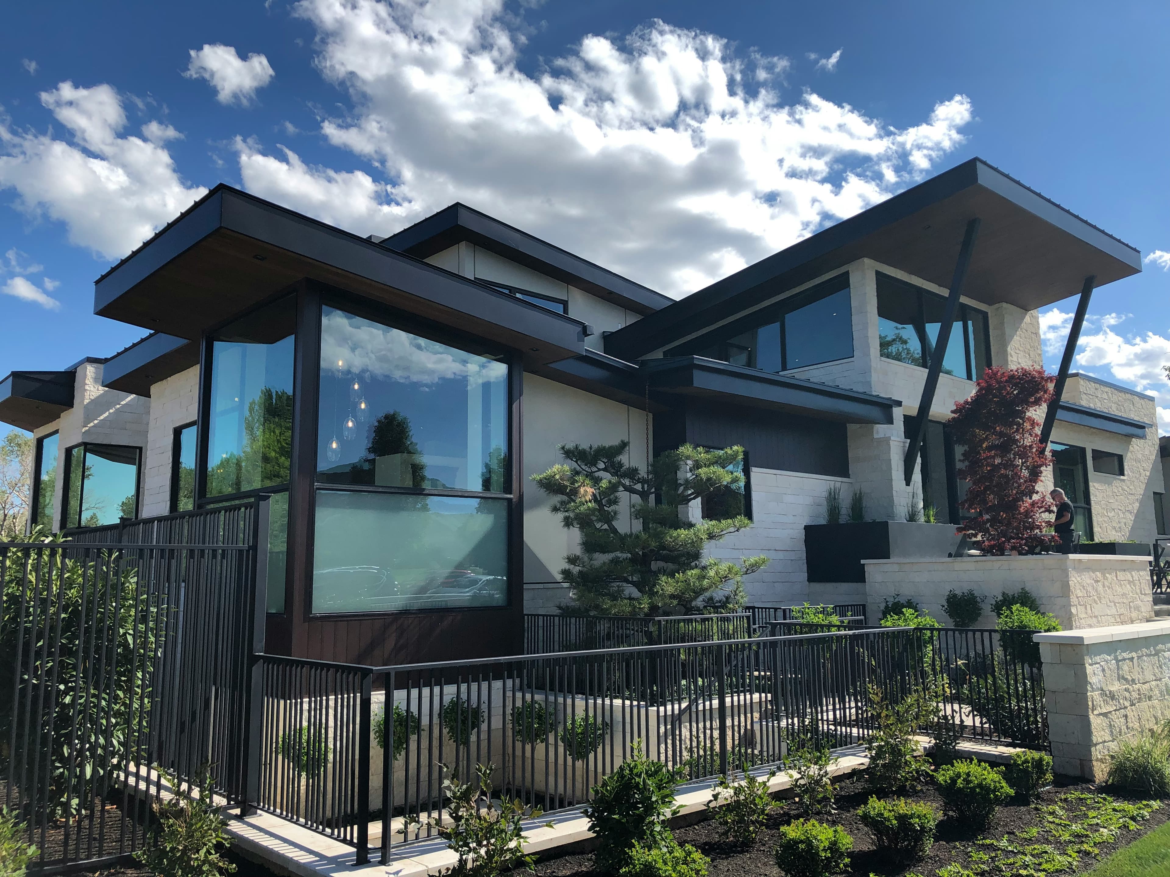 A contemporary two-storey home with deep overhanging roofs, floor-to-ceiling glass and a landscaped front garden
